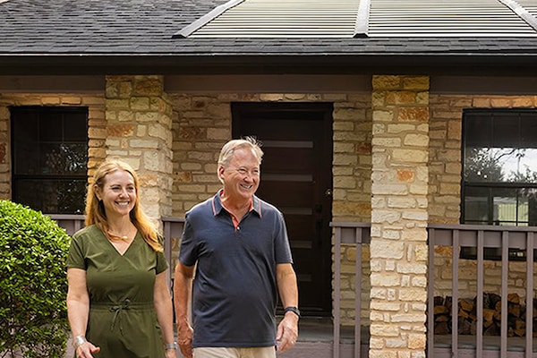 A homeowner couple in front of their home with a Timberline Solar roof system installed