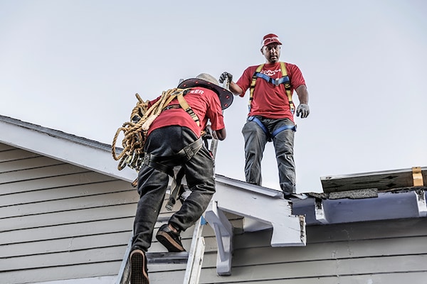 Volunteers wearing red t-shirts with The “Community Matters” logo on them work on a rooftop. 