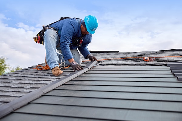 An installer working for a home builder is installing Timberline Solar ES 2 shingles on the roof of a new home.