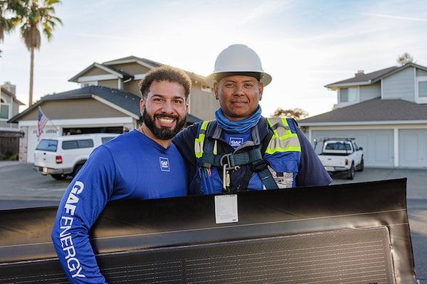 A solar certified contractor posing and smiling next to  a representative from the Energy Services team. 
