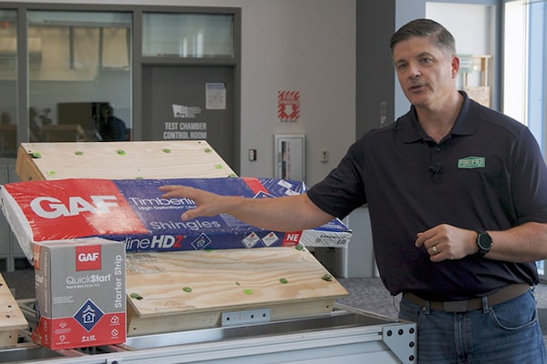 A representative wearing a shirt with the FORTIFIED ROOF logo demonstrating how certain GAF products comply with requirements. 