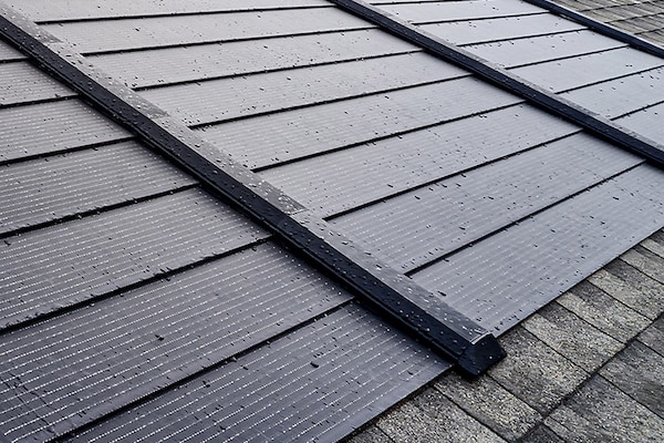 Black solar shingles made by GAF Energy on top of a roof built with Timberline brand asphalt shingles