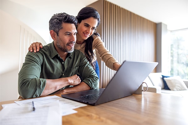 A homeowner couple looks at a roof cost estimate on their computer