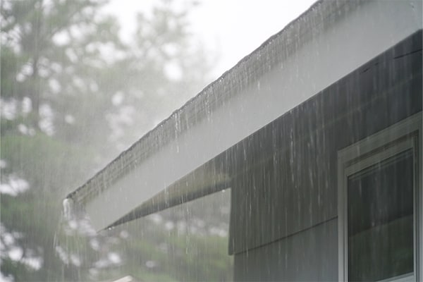 Heavy storm rains fall on roofing shingles, increasing the risk of long-term roof damage.