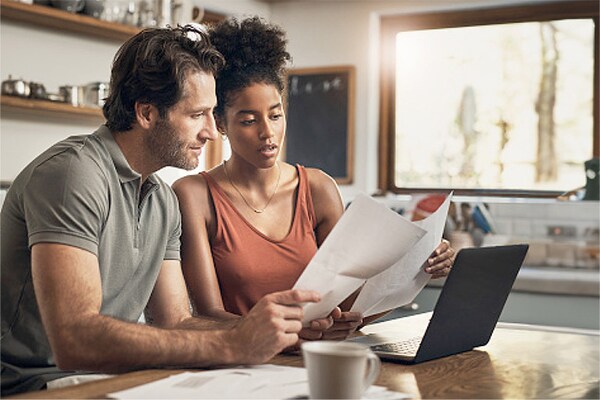 A couple reading their homeowners' insurance policy in the kitchen to check on roof damage coverage.