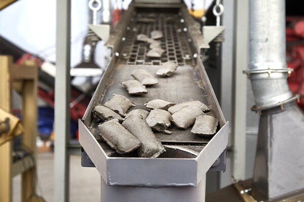 Asphalt shingle briquettes move along a conveyor belt as part of the GAF shingle recycling process.