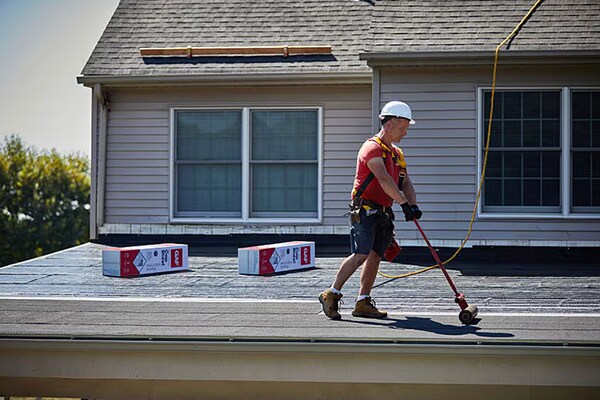 A roofer installs GAF LIBERTY™ Self-Adhering Base/Ply Sheet