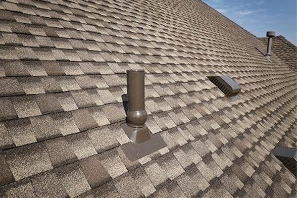 Side view of a metal chimney exhaust on asphalt roof with a cap