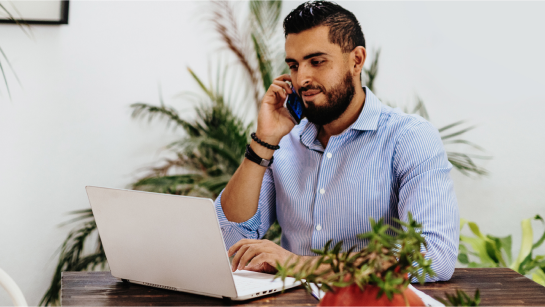 Man on phone in front of laptop