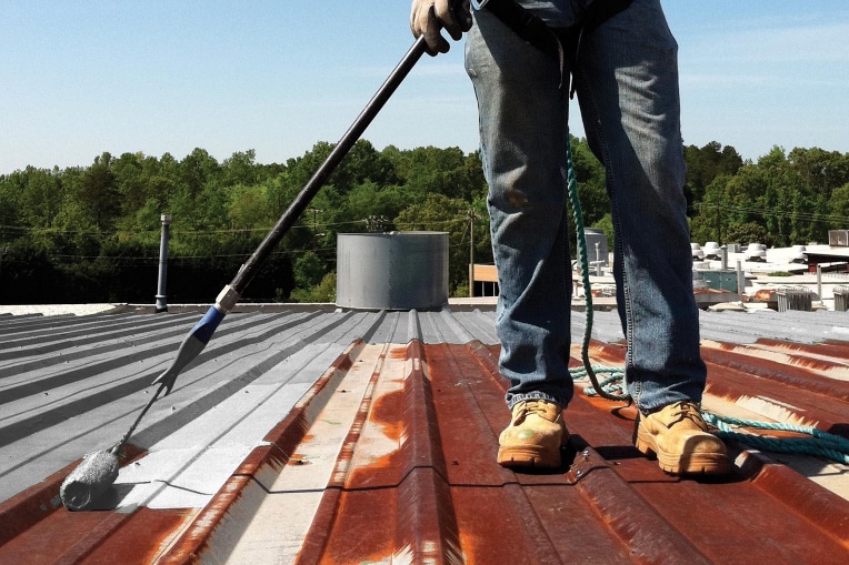 Contractor priming rusty areas of metal roof