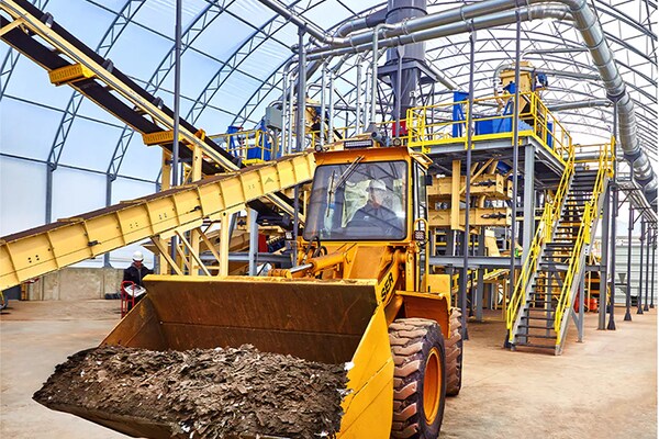 A tractor vehicle moves raw material through a GAF shingle recycling facility.