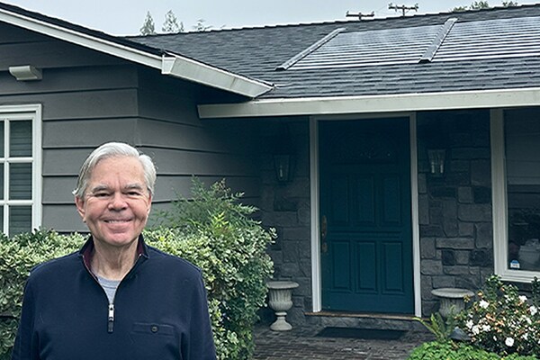 A homeowner standing in front of their home with a new GAF Energy Timberline Solar® Roof system