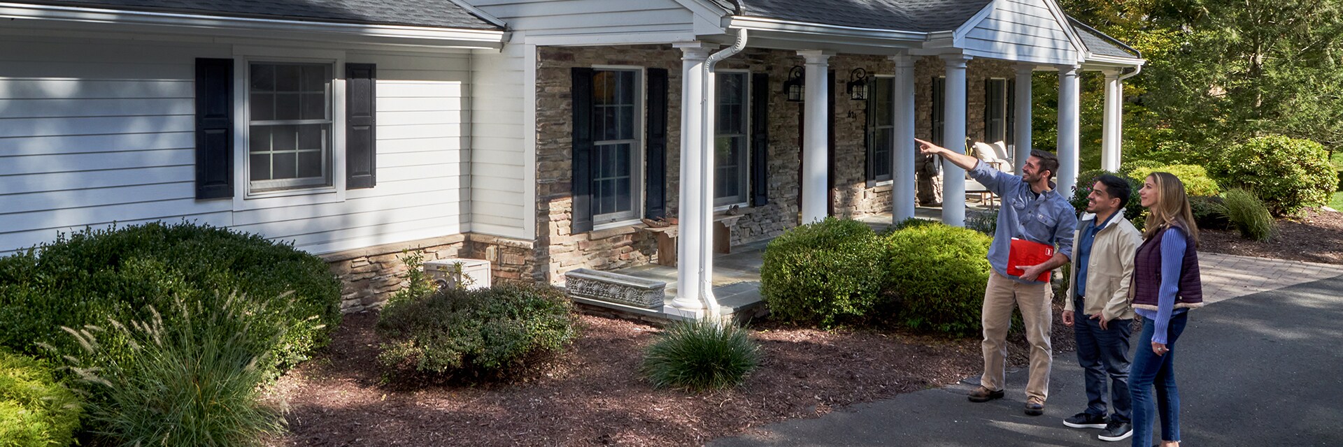 GAF certified roofer consulting with homeowners in front of their home