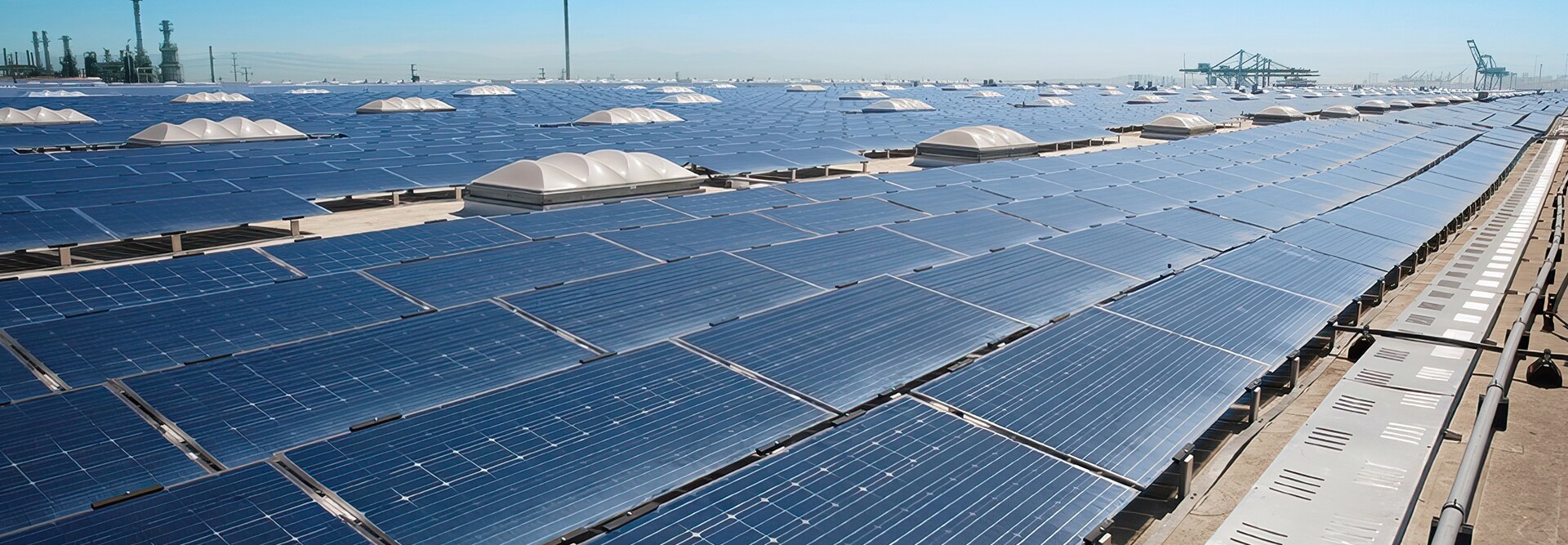 Large scale commercial rooftop solar panel installation stretching towards the horizon, featuring rows of photovoltaic panels.