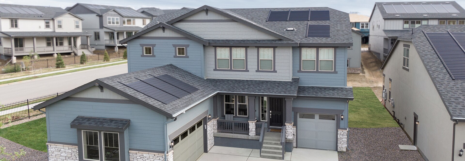 Aerial view of a blue and slate house, built by a local home builder, with a GAF Energy Timberline solar roofing system installed.