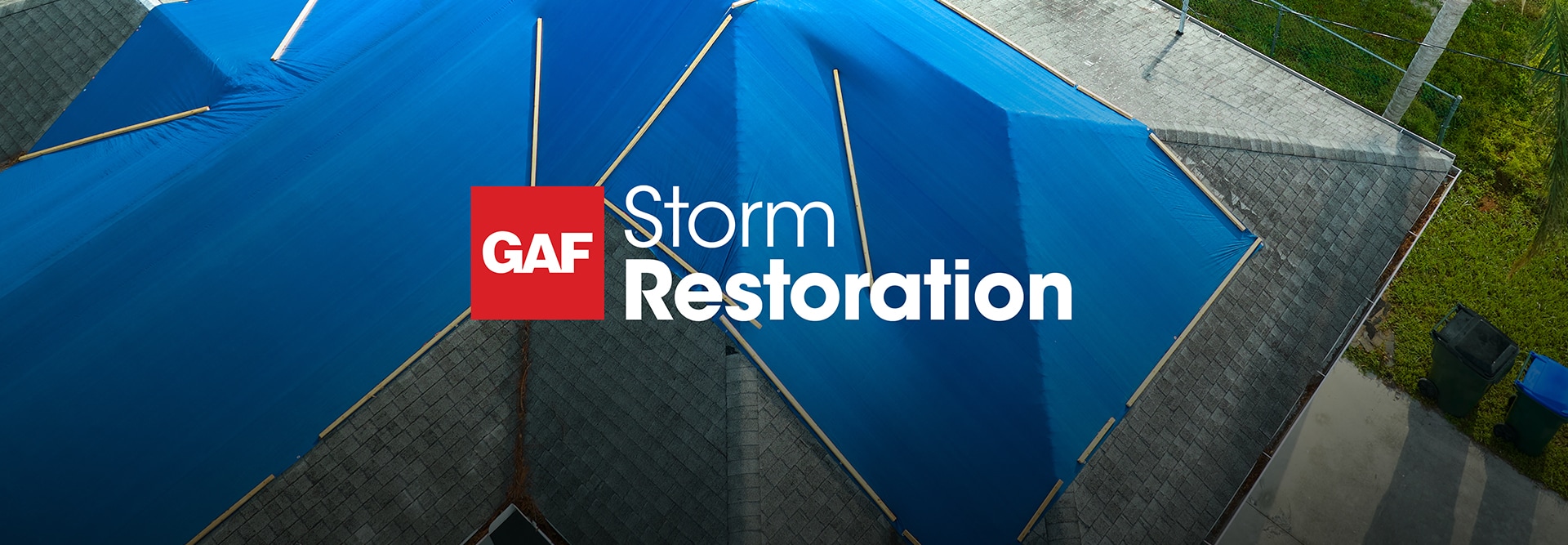 Aerial view of a home with a large blue tarp covering a damaged roof, featuring the GAF storm restoration logo at the top of the image.