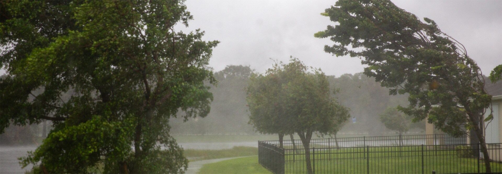 A residential neighborhood experiencing strong winds from a storm, where homes can benefit from the GAF WindProven Limited Wind Warranty that features no maximum wind speed limit.