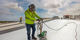 A GAF certified contractor using a stand-up robotic seam welder on an EverGuard PVC roofing membrane.