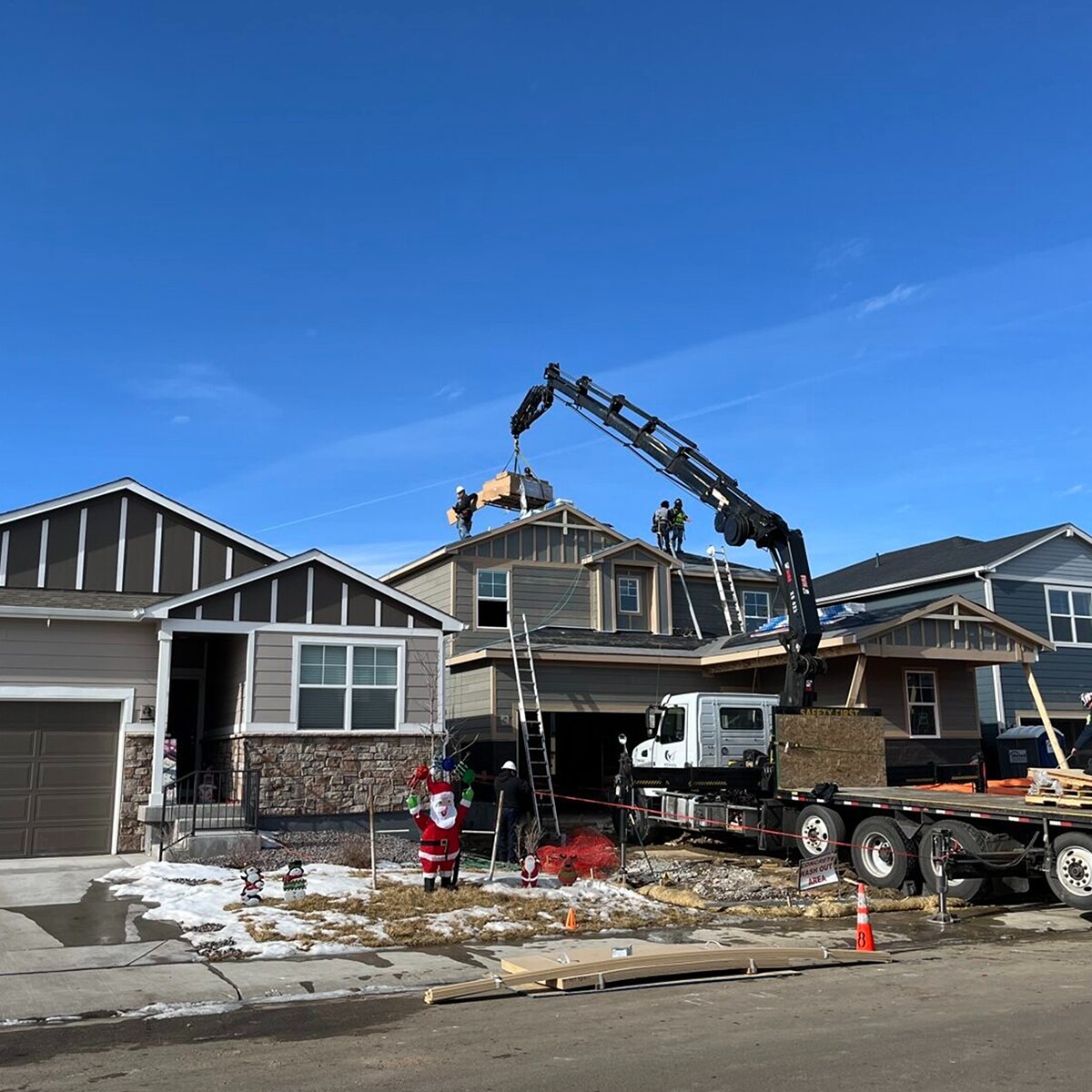 A boom truck operated by Meritage Homes is lifting materials onto the roof of a house under construction.