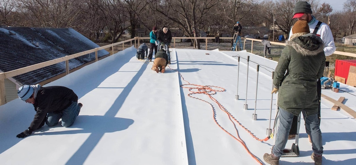 Students on roof installing GAF EverGuard 60 mil TPO and the RhinoBond attachment System