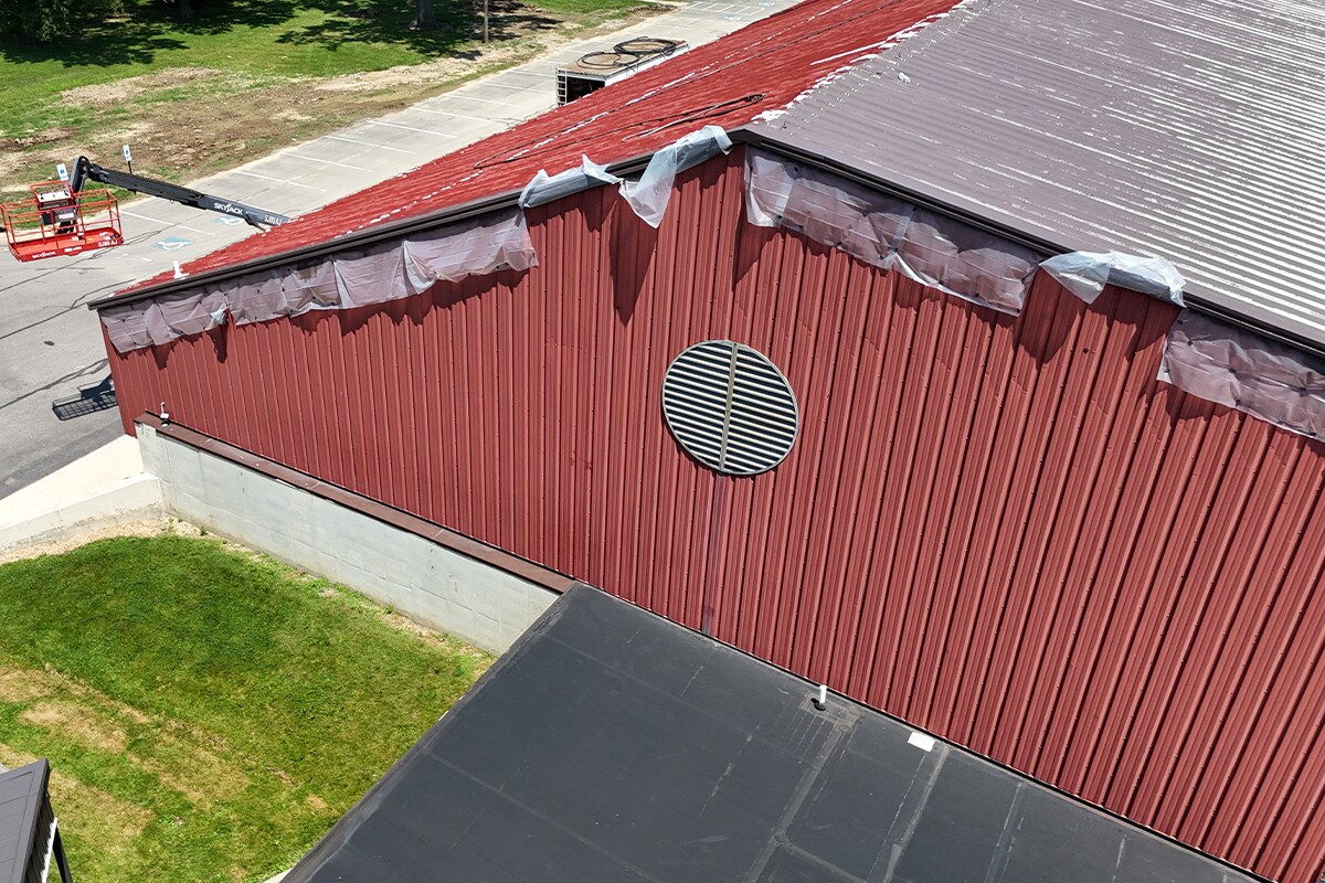 Side view of the old Elyria Ice Rink red roof and new silicone roof coating on the other half.