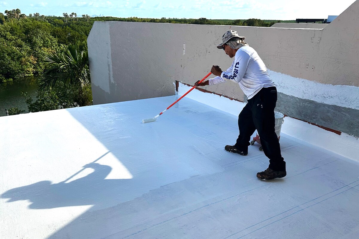 A GAF Coatings Pro+ Liquid Applied Roofing Contractor applying roof coating on a flat roof.