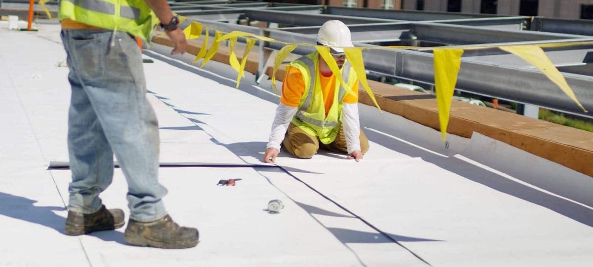 Construction workers installing a commercial roof with GAF materials