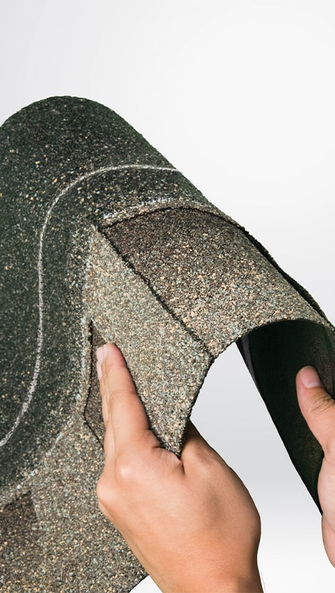 Hands bending a strip of Timberline ArmorShield II shingles, showing how flexible and durable it is.