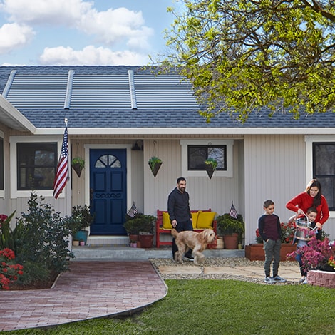 Familia delante de una casa con tejas solares GAF Energy