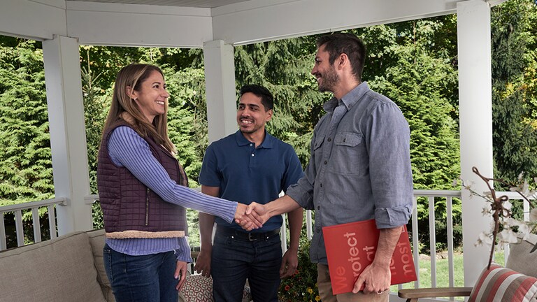 Roofing contractor shaking hands with homeowners