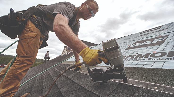 Contratista de techado certificado por GAF instalando tejas para techos con pistola de clavos