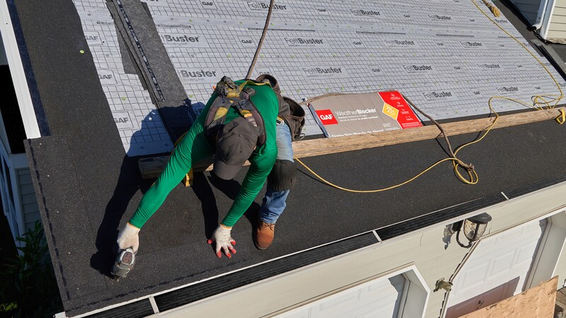 Roofer nailing WeatherBlocker to a residential roof.