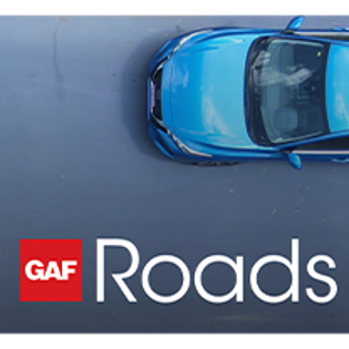Blue car driving on street with new GAF Roads roadway maintenance
